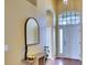Light-filled foyer with a decorative mirror, arched window, tiled floor and a neutral color palette for a welcoming entrance at 3116 Woodland Fern Dr, Parrish, FL 34219
