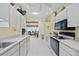 Galley kitchen with white cabinets, tile flooring, and modern appliances and fixtures at 4050 Oakhurst Dr # 3175, Sarasota, FL 34233