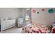 Bedroom with neutral paint, a white crib, armchair, dresser, and flower decor at 411 158Th E St, Bradenton, FL 34212