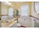 Bright bathroom featuring decorative mirror, window, and a neutral-toned countertop with white sink at 441 Rubens E Dr, Nokomis, FL 34275