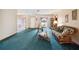 Bright living room with teal carpet, neutral walls, and sliding door access to the patio at 441 Rubens E Dr, Nokomis, FL 34275