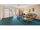 Cozy living room with a rocking chair, teal carpet, and sliding doors to a screened patio at 441 Rubens E Dr, Nokomis, FL 34275