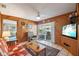 Inviting living room with wood paneling, ceiling fan, access to lanai through sliding doors, and comfortable seating at 441 Rubens E Dr, Nokomis, FL 34275