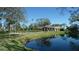 Clubhouse view with waterfront featuring an American flag, lush grass, and tropical palm trees at 4412 Spicewood Dr # D, Bradenton, FL 34208