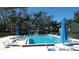 Community pool with lounge chairs and umbrellas surrounded by lush tropical trees under a clear blue sky at 4412 Spicewood Dr # D, Bradenton, FL 34208