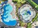 Aerial view of a community pool and splash pad surrounded by palm trees and lounge chairs at 4813 Sparkling Sea Ln, Lakewood Ranch, FL 34211