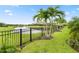 Backyard featuring a lake view, palm trees, manicured lawn, and a black fence at 4813 Sparkling Sea Ln, Lakewood Ranch, FL 34211
