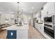 Modern kitchen with white cabinets, stainless steel appliances, large center island with quartz countertop, and decorative lighting at 4813 Sparkling Sea Ln, Lakewood Ranch, FL 34211