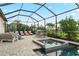 Screened-in pool area featuring a spa, outdoor seating, a grill, and lush tropical landscaping at 4813 Sparkling Sea Ln, Lakewood Ranch, FL 34211