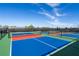 View of a tennis court with green, blue, and red sections under a partially cloudy sky at 4813 Sparkling Sea Ln, Lakewood Ranch, FL 34211
