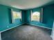 Empty bedroom showcasing teal walls, multiple windows, and neutral carpet floors at 503 Philodendron, Punta Gorda, FL 33955