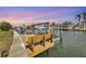 Waterfront dock with boat lift and bench seating overlooking tranquil canal waters at sunset at 5112 Arlington Rd, Palmetto, FL 34221