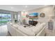 Bright living room featuring an L-shaped white sofa, tile flooring, sliding glass doors, and decorative accents at 5313 Halewood Ct, Bradenton, FL 34211