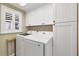 Well-equipped laundry room featuring a washer, dryer, and ample white cabinetry for storage and organization at 6140 Midnight Pass Rd # A10, Sarasota, FL 34242