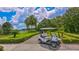 Clean white golf cart parked on a paved path surrounded by manicured landscaping and a serene lake view at 7849 Wilton Crescent Cir, University Park, FL 34201