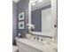 Stylish powder room with blue textured wallpaper, marble countertop, and framed mirror at 8077 Tidal Pointe Way, Sarasota, FL 34240