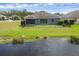 View of a home's backyard featuring a serene pond, a well-kept lawn, and a black fence at 815 Rosemary Cir, Bradenton, FL 34212
