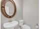 Powder room features pedestal sink, oval mirror with decorative frame, and white toilet at 815 Rosemary Cir, Bradenton, FL 34212