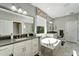 Luxury bathroom featuring double sinks, walk-in shower, soaking tub, and large mirrors for enhanced functionality at 12026 Perennial Pl, Bradenton, FL 34211