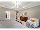 Well-appointed main bedroom with tray ceiling, dresser, sitting area, and access to a walk-in closet at 12026 Perennial Pl, Bradenton, FL 34211