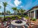 Inviting fire pit with chairs surrounded by palm trees and a clubhouse in the background at 12404 Golden Sage Dr, Sarasota, FL 34238