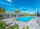 Community swimming pool with lounge chairs, umbrellas, and a clubhouse in the background at 12404 Golden Sage Dr, Sarasota, FL 34238