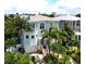 Charming light blue two-story home with garage, balconies, white trim, and lush tropical landscaping at 130 50Th St, Holmes Beach, FL 34217