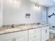Bathroom features double sinks, a granite countertop and white cabinets, with a decorative mirror and sconces at 13365 Drayton Dr, Spring Hill, FL 34609
