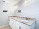 Bathroom features double sinks, a granite countertop and white cabinets, with a decorative mirror and sconces at 13365 Drayton Dr, Spring Hill, FL 34609
