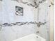 Bright bathroom features gray and white marble tiling, a shower head and built-in niche at 13365 Drayton Dr, Spring Hill, FL 34609