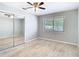 Bright bedroom features a ceiling fan, a large window, and closet with mirrored sliding doors at 13365 Drayton Dr, Spring Hill, FL 34609