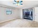 A spacious room with tiled floor, a ceiling fan, a window, and a sliding glass door to an outdoor patio at 13365 Drayton Dr, Spring Hill, FL 34609