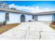 Front exterior view of a home featuring a long driveway, a garage, and an arched entry at 13365 Drayton Dr, Spring Hill, FL 34609