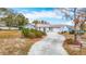 Inviting front exterior featuring mature trees, a long driveway, and landscaping at 13365 Drayton Dr, Spring Hill, FL 34609