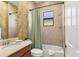 Bathroom featuring a sink, commode, and shower-tub combo with earth-toned tile at 15606 Leven Links Pl, Lakewood Ranch, FL 34202