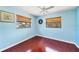 Bedroom featuring wood floors, blue walls, a ceiling fan, and two large windows with wooden blinds at 3208 Vivienda Blvd, Bradenton, FL 34207