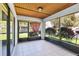 Enclosed patio with tile floors, screened windows, and a wood plank ceiling and view of landscaping at 3208 Vivienda Blvd, Bradenton, FL 34207
