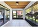 Enclosed patio with tile floors, screened windows, and a wood plank ceiling and view of landscaping at 3208 Vivienda Blvd, Bradenton, FL 34207