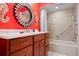 Bright bathroom with red walls, decorative mirror, wood vanity, and tiled shower at 3296 Tallywood Ct # 7097, Sarasota, FL 34237