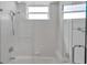 White tiled shower and tub combo with glass door and window for natural light at 3617 Fair Oaks Pl, Longboat Key, FL 34228