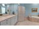Bright bathroom featuring a glass block shower, soaking tub, and stylish vanity at 3617 Fair Oaks Pl, Longboat Key, FL 34228