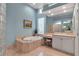 Bright bathroom featuring a soaking tub with tile surround, glass block window, and vanity with makeup area at 3617 Fair Oaks Pl, Longboat Key, FL 34228