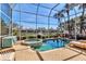Screened-in pool area with a hot tub, lounge chairs, and lush landscaping and lake views at 3617 Fair Oaks Pl, Longboat Key, FL 34228