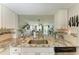 Bright kitchen boasts granite countertops, stainless sink, white cabinets, and a pass-through to the living area at 3805 E Bay Dr # 301, Holmes Beach, FL 34217