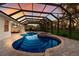A view of the screened-in pool and backyard with an integrated hot tub and stone surround at 3902 162Nd E Ave, Parrish, FL 34219
