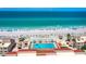 An aerial view of the pool with beach access, tiki huts, and blue umbrellas on a sunny day at 4621 Gulf Of Mexico Dr # 19B, Longboat Key, FL 34228