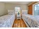 Bedroom with two white beds, wood floors, a lamp on a nightstand, and a window at 5007 Palermo Dr, Punta Gorda, FL 33950
