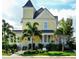 Charming Victorian-style house with a yellow exterior, wraparound porch, and lush landscaping with palms at 5007 Palermo Dr, Punta Gorda, FL 33950