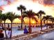 A beach view shows people enjoying the sunset with palm trees in foreground at 5007 Palermo Dr, Punta Gorda, FL 33950