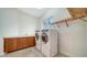 Bright laundry room features a modern washer and dryer, storage cabinets, and a convenient folding rack at 5169 Sandy Shore Ave, Sarasota, FL 34242